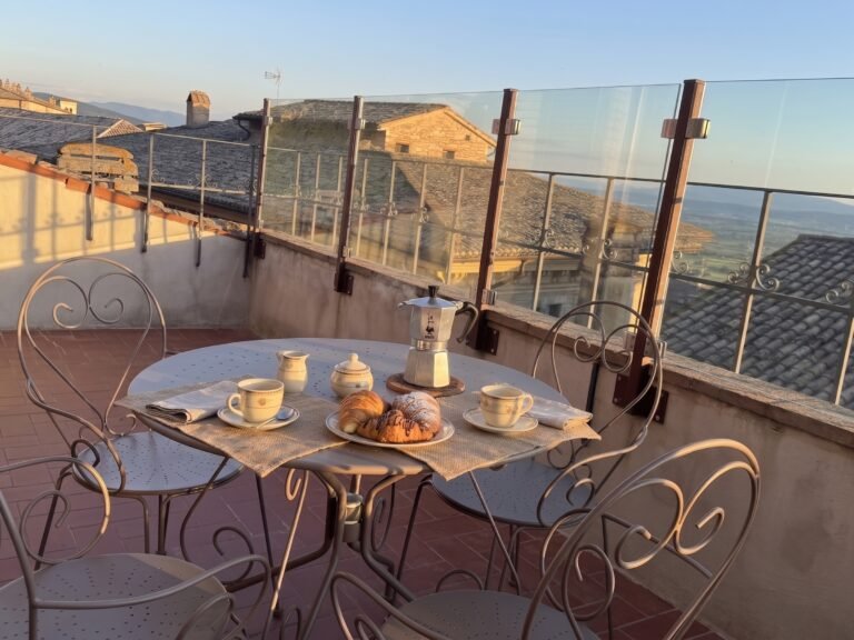 Terrazza panoramica dell'attico Luce ad Assisi con tavolo apparecchiato per la colazione e vista sulla Valle Umbra
