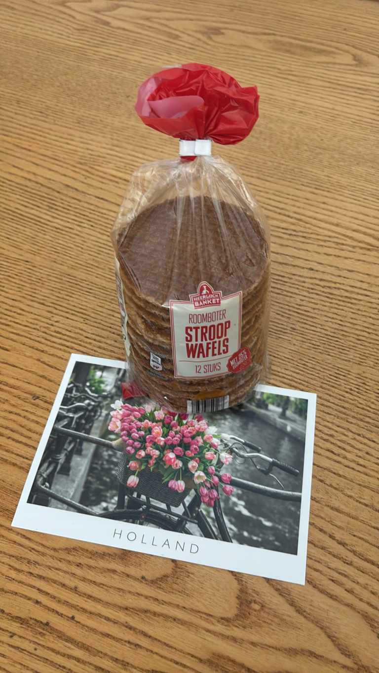 Confezione di stroopwafel olandesi e cartolina Holland con biciclette e tulipani su un tavolo in legno